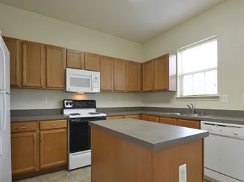 Kitchen with white appliances and wooden cabinets at The Pointe at Manorgreen Townhomes, Baltimore, MD